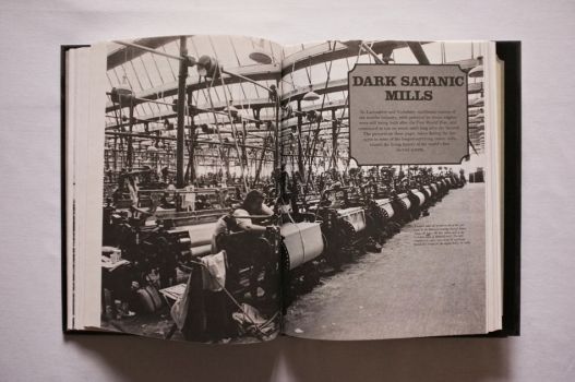 The opening scene in a picture essay on Satanic Mills is a black-and-white photograph of the interior of the Bancroft weaving shed at James Nutter & Sons’ cotton mill in the Yorkshire town of Barnoldswick. In the foreground a weaver takes up an end on one of 500 looms powered by belts running from overhead shafts.