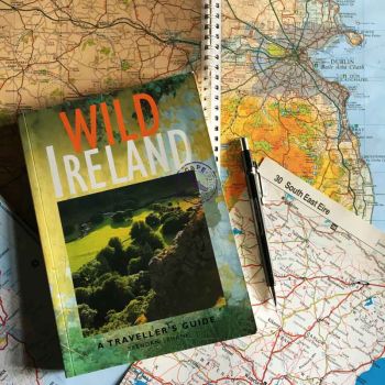 A copy of Wild Ireland and a pencil lie on an open atlas. 