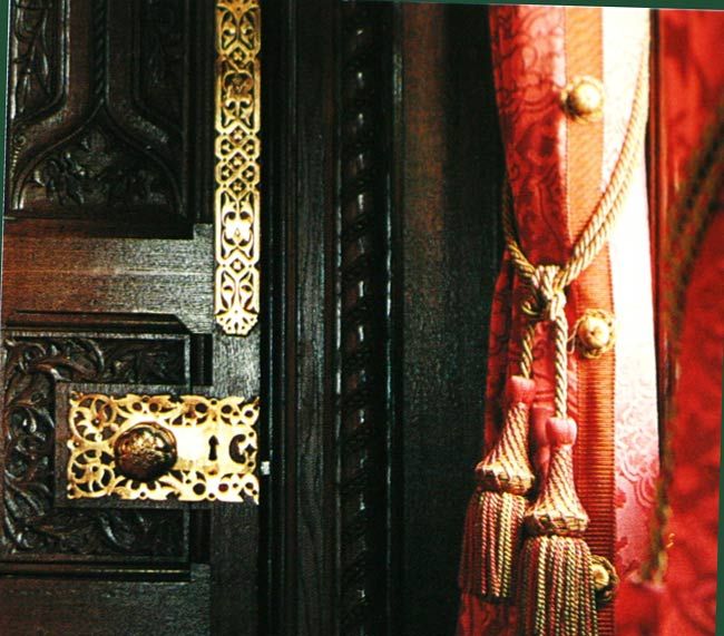 Colour photograph of richly patterned and tasselled red curtains in the Speaker's House at the Palace of Westminster.