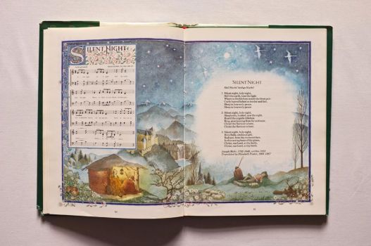 An illuminated double-page spread from A Book of Christmas Carols provides the words and music of Silent Night. 