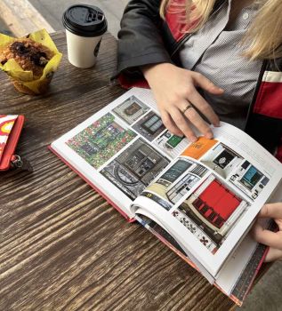 In this colour photograph, a reader opens the book ‘Doors of London’ to a double-page spread featuring ten doors in Mayfair. 