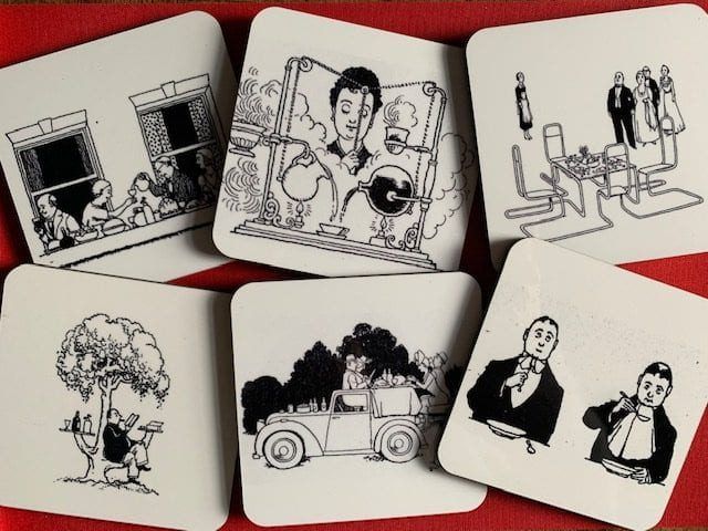 Photograph of the set of six Heath Robinson coasters, illustrated with back and white line drawings and set against a red background.
