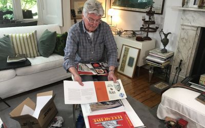 Colour photograph of a big moment when the designer Ian Logan, seated in his sitting room, sees the printed proofs of his book Logomotive for the first time.