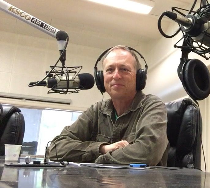 In this colour photograph Gary Shapiro, presenter of From the Bookshelf, wears headphones as he prepares to speak into a boom mike at his desk in KSCO radio station, Santa Cruz.