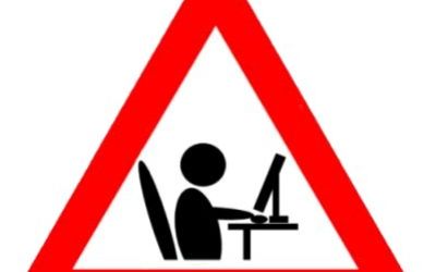 Red and white triangular warning sign with a stick figure at work on a computer.