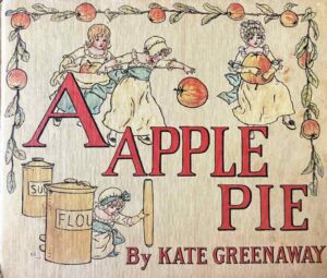 On the cream front cover of ‘A Apple Pie’ by Kate Greenaway children in long dresses with blue sashes gather red apples, sugar, flour and a rolling pin to bake themselves a pie. The title of the book is printed on three lines in a red seriph font with a black outline.