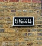A sign for Step Free Access uses an LNWR font in white capitals on a black background and a traditional pointing finger