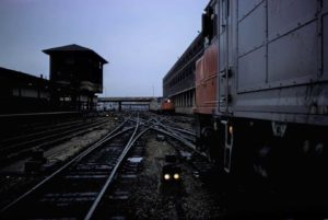 In this 1975 colour photograph shot at dusk, locomotives move up and down a complex track layout in the West 60th Street freight yard in New York. Looming on the left is the control tower.