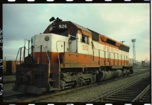 In the Kansas City Burlington Yards, the driver of Frisco SD45 locomotive 926 has detached his engine from his train and brought it forward for Ian Logan to photograph. The engine wears the Frisco orange and white livery, and the driver leans from the window.