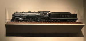 In this colour photograph a model of a Hudson type locomotive with the name New York Central on its tender is displayed in a glass case at the Albany Institute of History & Art.  