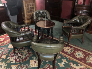 A colour photograph of a round table and four leather-backed chairs standing on a Turkey carpet marks the place where Sheldrake Press had their first meeting with the co-author of ‘Doors of London’, Melanie Backe-Hansen.