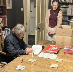 In this colour photograph taken in the Publisher’s study at Sheldrake Press, Jonathan Glancey signs a copy of ‘Logomotive’ watched by members of the editorial team. 
