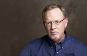 In this colour photograph, Kevin P. Keefe, director of the Center for Railroad Photography and Art and former editor-in-chief of Trains magazine, looks towards the camera, wearing a blue shirt, for a professional headshot.