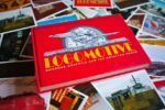 Ian Logan’s book Logomotive lies on an array of postcards created from period photographs and ephemera.