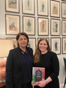 In this colour photograph taken in the Authors’ Club in London, Cath Harries and Melanie Backe-Hansen pose with their new book ‘Doors of London’ in front of a wall hung with framed 19th-century cartoons.