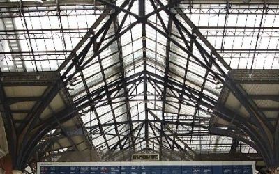 In this photograph of the interior of Liverpool Street Station, light foods through the ironwork of the concourse roof.
